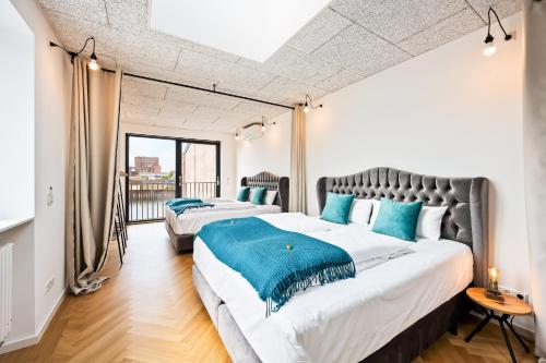 two beds in a room with a large window at Lit Living - Luxus Loft - Box Spring - Air Con - BBQ - Panorama in Mannheim