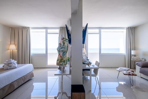 a white room with a bed and a table and windows at ON Hotels Oceanfront Adults Designed in Matalascañas