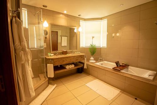 a bathroom with a tub and a sink and a bath tub at Sands Suites Resort & Spa in Flic-en-Flac