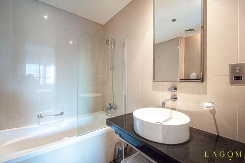 a bathroom with a sink and a bath tub at Lagom Vacation Homes 1 & 2 bedroom Apartment in Bonnington Tower, cluster J in Dubai