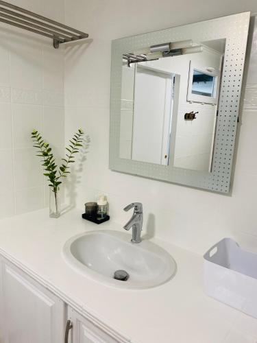 a white bathroom with a sink and a mirror at Etape du soleil in Lunel