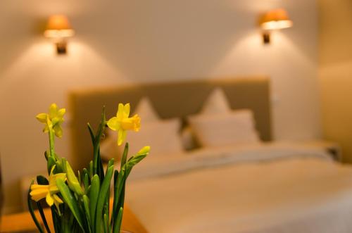 um vaso com flores amarelas em frente a uma cama em De Groote Waere em Diksmuide