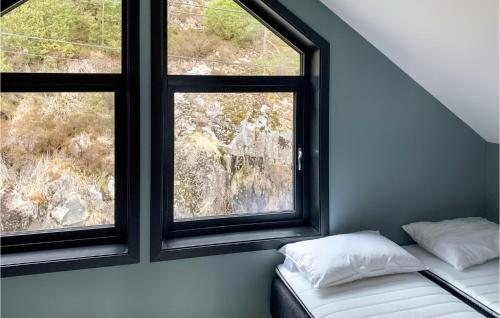 a bed in a room with two windows at Lovely Home In Hebnes With House Sea View in Hebnes
