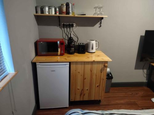 a small wooden counter with a microwave and a refrigerator at Old Eden House in Rossbeg