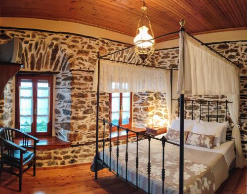 a bedroom with a bed in a room with stone walls at TERPOU Stonehouse & Suites in Áyios Vlásios