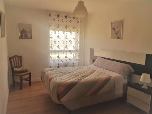 a bedroom with a bed and a window and a chair at Excelente apartamento en el Pirineo aragonés in Sabiñánigo