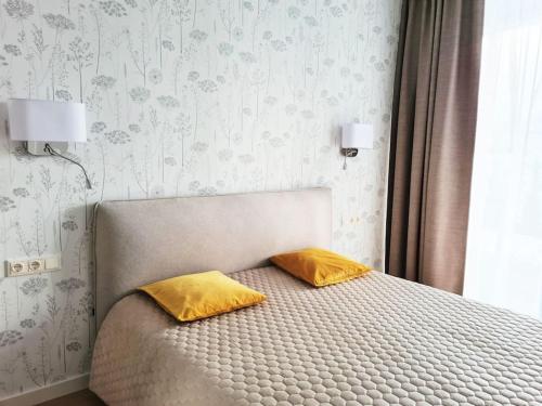 um quarto com uma cama com duas almofadas amarelas em Parko Aveniu Apartamentai em Birstonas