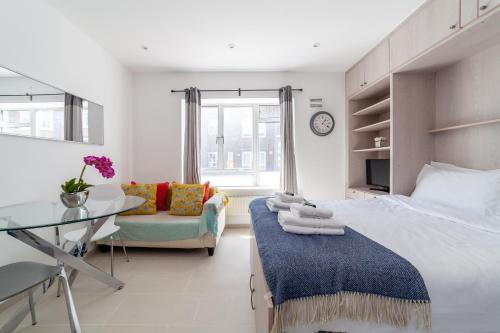 a bedroom with a large bed and a glass table at Bright Studio Flat in the Heart of Marylebone in London
