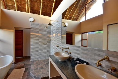 uma casa de banho com 2 lavatórios e um espelho grande em Black Rhino Game Lodge em Pilanesberg