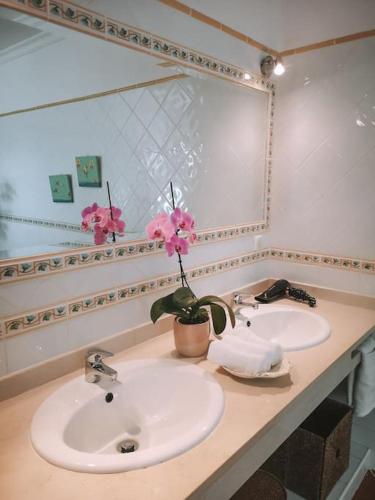 a bathroom with two sinks and a mirror and pink flowers at Green Ville in Faro