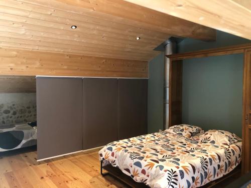 une chambre avec un lit et un plafond en bois dans l'établissement Les vieilles pierres drômoises, à Alixan