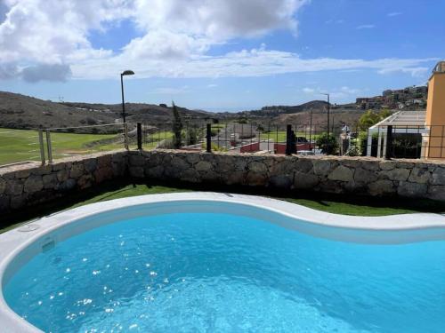 a swimming pool with a stone retaining wall at Sea View Villa Vista Golf in Salobre