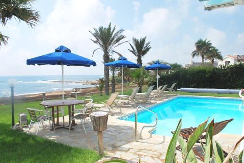 een zwembad met stoelen, tafels en parasols bij Sea Front Villa With Private Heated Pool, Quiet area Paphos 322 in Kissonerga