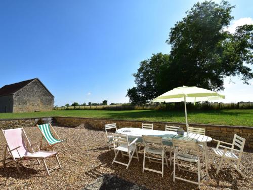 a table with chairs and an umbrella in a yard at Mansion in Burgundy near Morvan Natural Park in Moussy