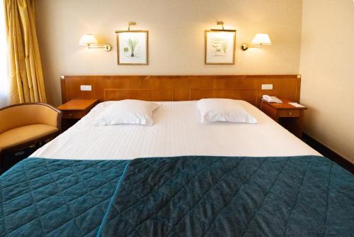 a bedroom with a large bed with two tables and a chair at Splendid Hotel & Spa Nice in Nice