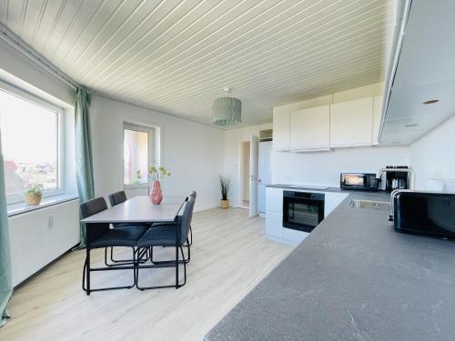 a kitchen with a table and chairs in a room at aday - Greenway 2 bedrooms apartment in Frederikshavn