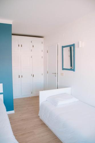 a white bedroom with two beds and white cabinets at Arca Nova Guest House - Caminha in Caminha