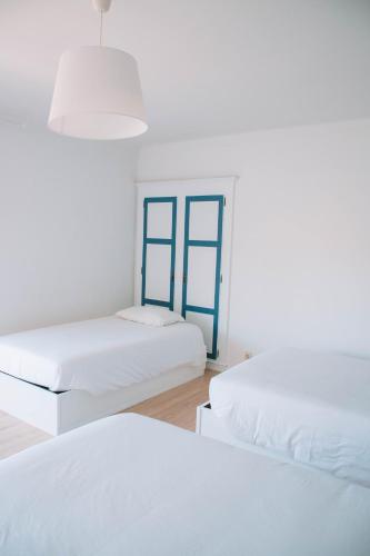 two beds in a white room with blue windows at Arca Nova Guest House - Caminha in Caminha