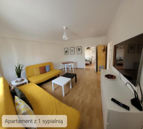 a living room with a yellow couch and a table at LuLu Apartamento Centro in Łagów