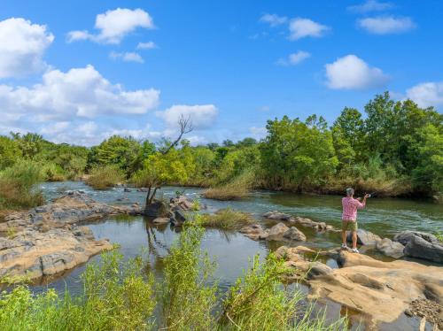 a man standing on rocks in a river at Oase by 7 Star Lodges - Greater Kruger Private 530ha Reserve in Hoedspruit