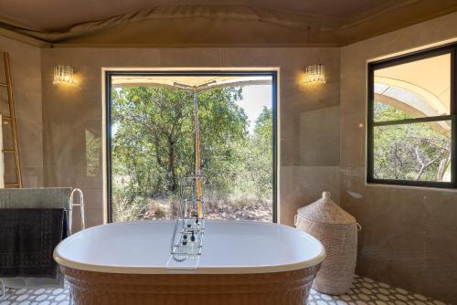 a large bath tub in a bathroom with a window at Oase by 7 Star Lodges - Greater Kruger Private 530ha Reserve in Hoedspruit