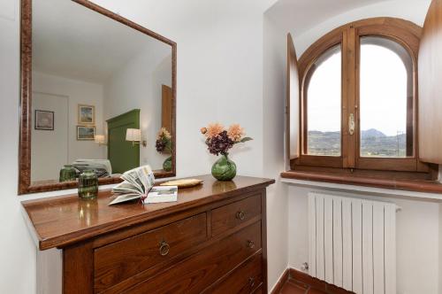 a dresser with a mirror and a vase with flowers on it at Smeraldo in Spello