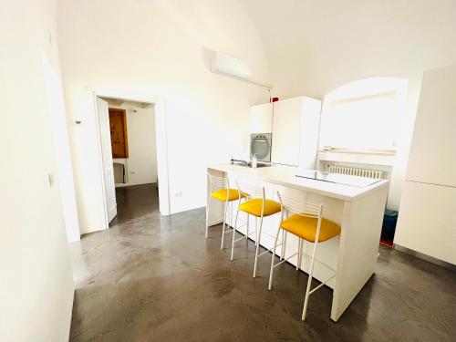 uma cozinha branca com cadeiras amarelas e um balcão em View - Art house Roof top sea view em Polignano a Mare