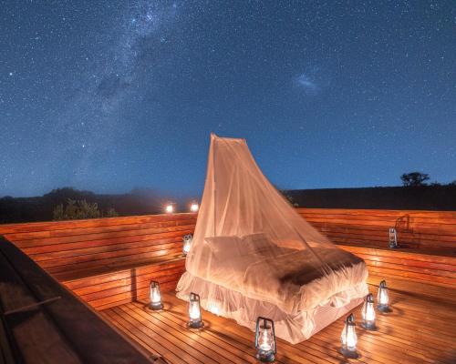 a bed on a wooden deck at night with lights at Oase by 7 Star Lodges - Greater Kruger Private 530ha Reserve in Hoedspruit