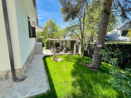 a yard with grass and a tree next to a house at La Fontanilla en Estación de El Espinar in Segovia