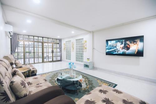 ein Wohnzimmer mit einem Sofa und einem Fernseher an der Wand in der Unterkunft 4BR Villa, 6min to Lee Garden, 22 PAX - Paradise Found in Hat Yai