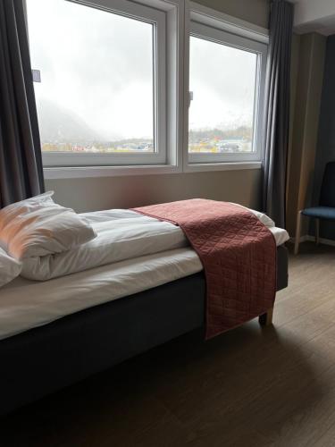 a bed in a room with two large windows at Frichs Ekspress Åndalsnes in Åndalsnes