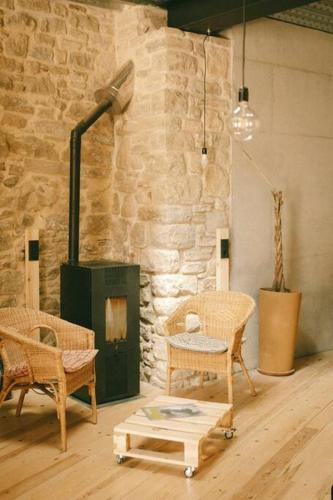 Habitación con sillas de mimbre y pared de piedra. en inLoft Copons en Copóns
