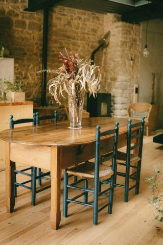 una mesa de madera con sillas y un jarrón con flores en inLoft Copons en Copóns