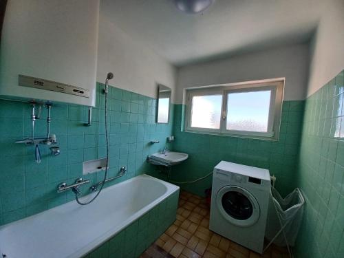 a green bathroom with a tub and a washing machine at BrightCenterApartment in Graz