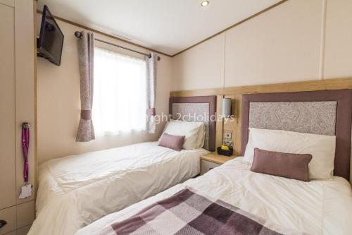 a bedroom with two beds and a window at Stunning 8 Berth Caravan With Sea Views Decking At Hopton-on-sea Ref 80004h in Great Yarmouth