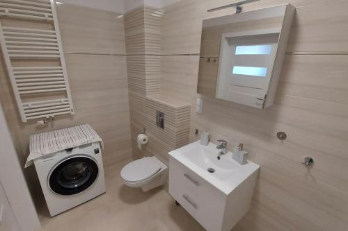 a white bathroom with a washing machine and a sink at Nowiutki apartament z bezpłatnym parkingiem in Rumia