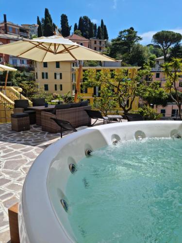 a jacuzzi tub on a patio with an umbrella at Hotel Canali, Portofino Coast in Rapallo