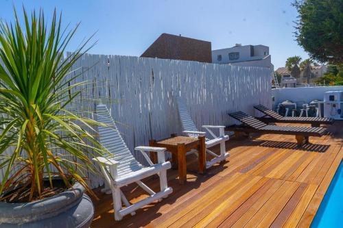 a deck with chairs and a table and a fence at 7th Wonder Beach Guest House in Cape Town