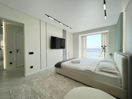 Un dormitorio blanco con una cama grande y una ventana en LUX с видом на набережную, en Pavlodar