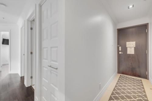 a hallway with white walls and a door at INITIAL - HORIZON - Chutes-Montmorency in Boischâtel