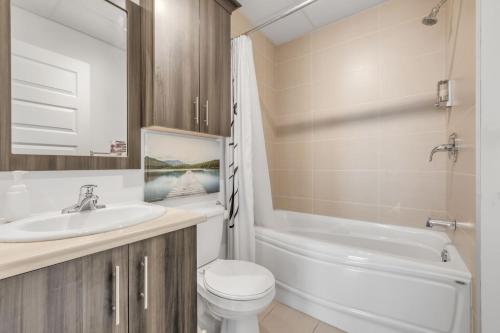 a bathroom with a sink and a toilet and a tub at INITIAL - HORIZON - Chutes-Montmorency in Boischâtel