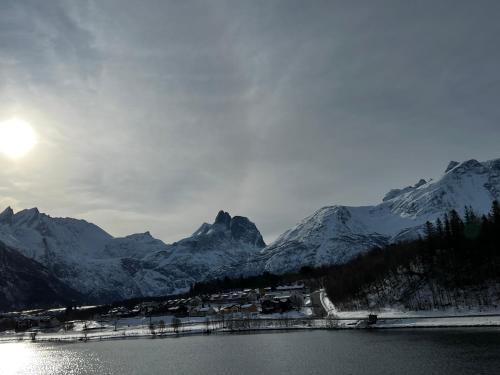 a snow covered mountain range with a body of water at Frichs Ekspress Åndalsnes in Åndalsnes