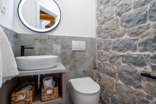 a bathroom with a sink and a toilet and a mirror at New! Charming Villa Perina with private heated pool in Tugare
