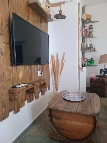 a living room with a tv and a wooden table at Vlami's House Andros in Apróvaton