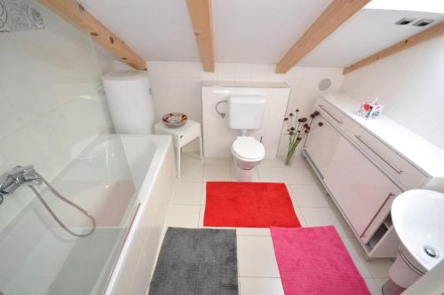 een badkamer met een bad, een toilet en een rood tapijt bij Villa Magalia in Bol