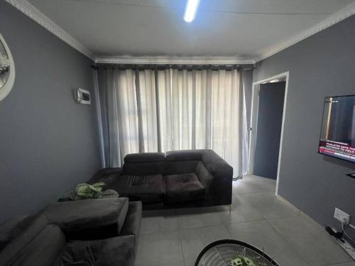 - un salon avec un canapé et une télévision dans l'établissement Ubuntu Lifestyle Estate, à Krugersdorp