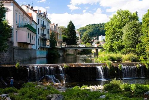 a waterfall in the middle of a river with buildings at Appartement sur Vals les bains in Vals-les-Bains