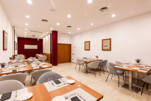 a dining room with wooden tables and chairs at Catalonia Gran Hotel Verdi in Sabadell