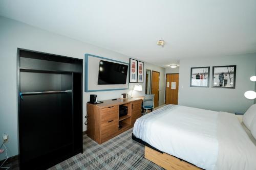 a hotel room with a bed and a desk and a tv at AmericInn by Wyndham Tomahawk in Tomahawk