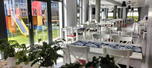 a restaurant with white chairs and tables and windows at Pensjonat Latino in Rowy